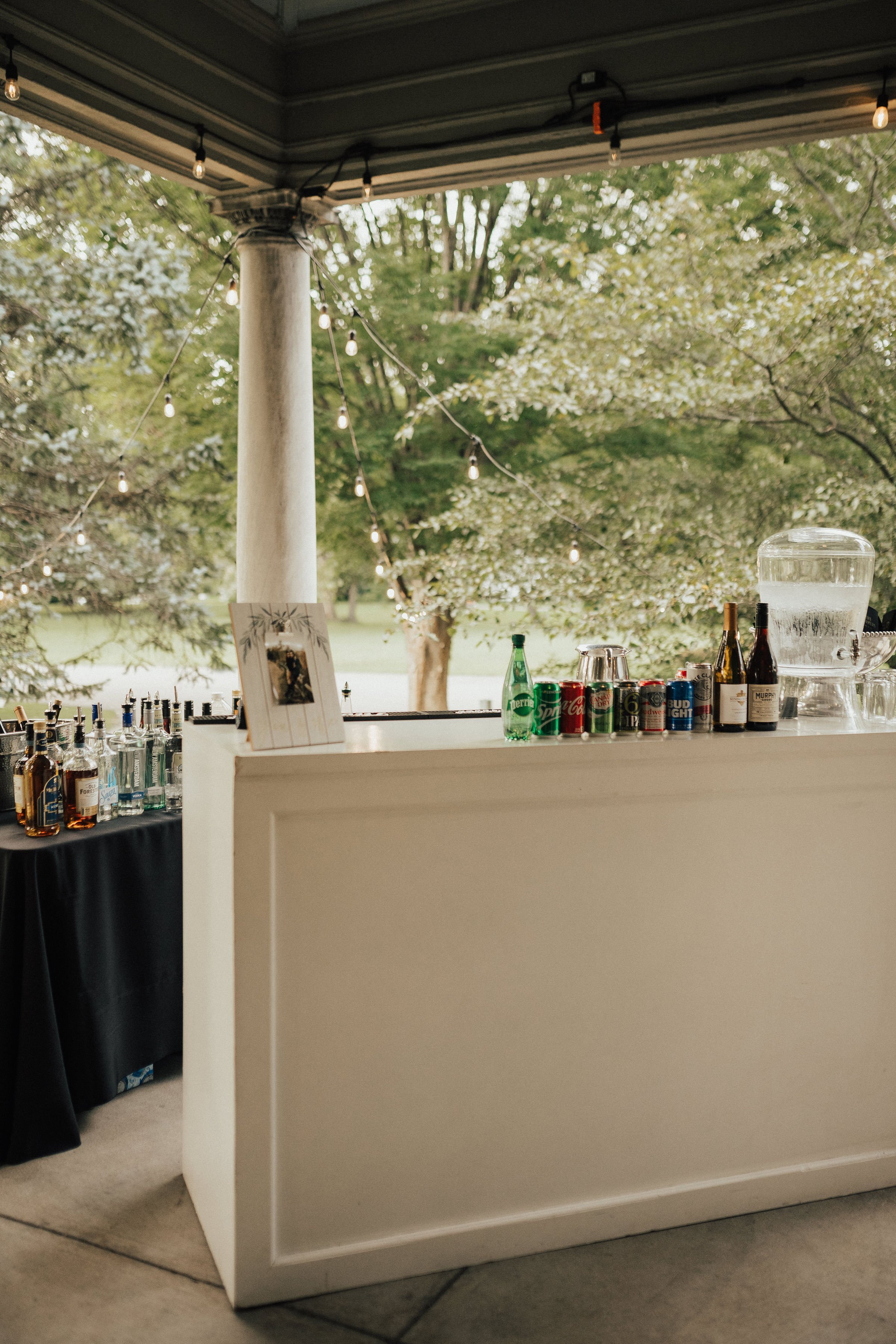 Full bar setup under the veranda with string lights