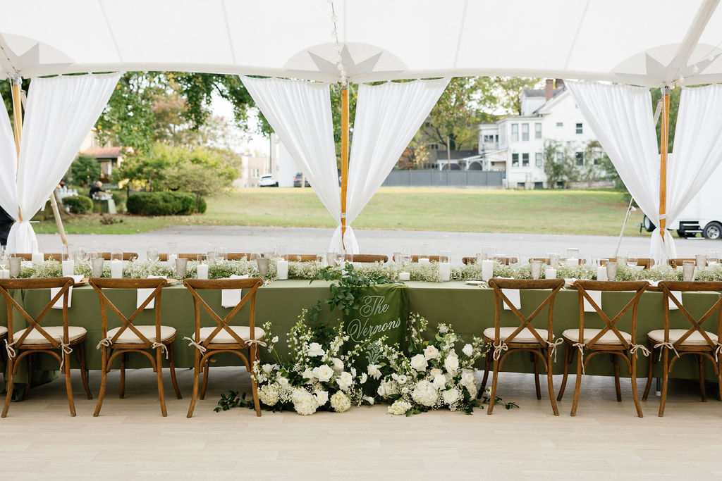 Tented reception with white drapes and floral arrangements